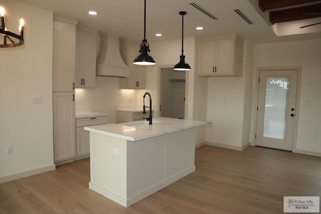 13953 Isaiah Ct, La Feria, TX 78559 - kitchen with premium range hood, light wood finished floors, white cabinetry, recessed lighting, and light countertops