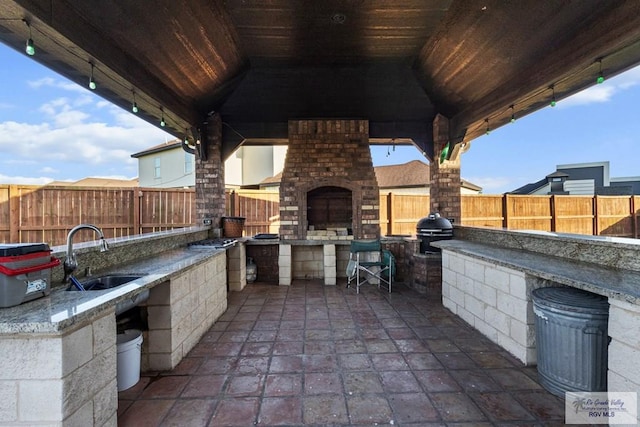 2540 Los Portales Dr, Brownsville, TX 78526 - fenced backyard with exterior fireplace, a gazebo, a sink, and a patio area