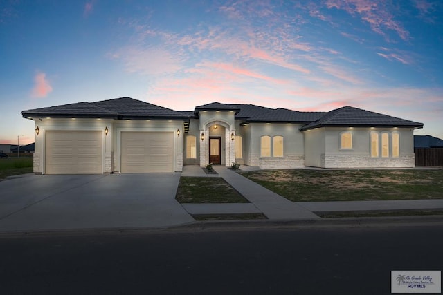 5407 Common Ln, Weslaco, TX 78596 - view of front facade featuring an attached garage, concrete driveway, stone siding, and stucco siding