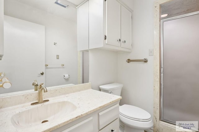 bathroom featuring a shower with door, vanity, and toilet