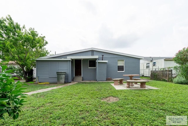 802 California St, Harlingen, TX 78552 - rear view of property featuring a patio, brick siding, fence, and a lawn