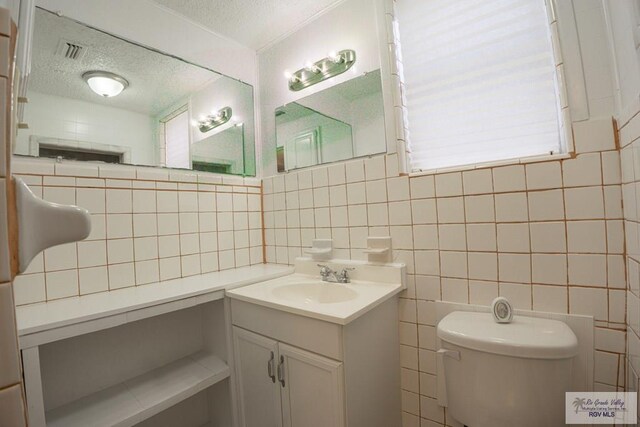 802 California St, Harlingen, TX 78552 - half bathroom featuring decorative backsplash, toilet, vanity, visible vents, and a textured ceiling