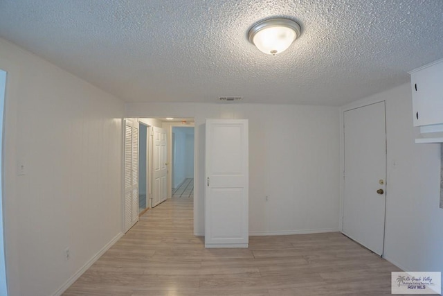802 California St, Harlingen, TX 78552 - empty room featuring baseboards, visible vents, light wood-style floors, and a textured ceiling
