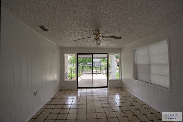 802 California St, Harlingen, TX 78552 - empty room featuring ceiling fan, wooden walls, visible vents, baseboards, and a textured ceiling