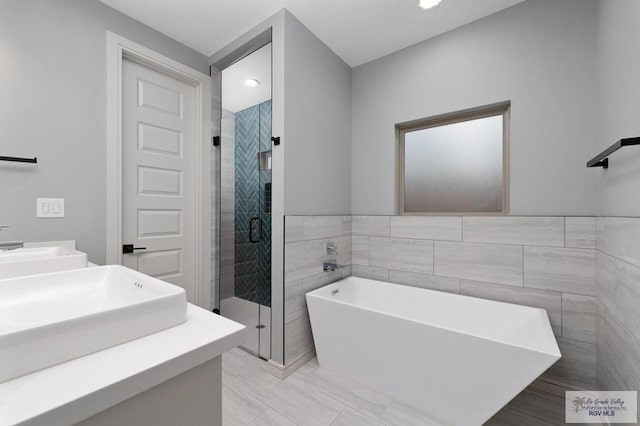 2009 New Combes Rd, Harlingen, TX 78550 - full bathroom featuring a freestanding tub, vanity, a shower stall, tile walls, and recessed lighting