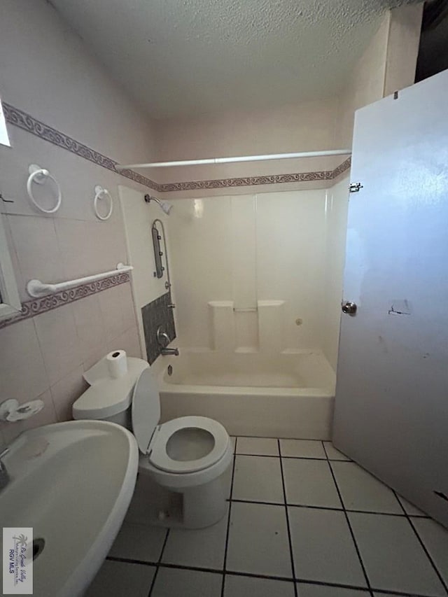 full bathroom featuring bathtub / shower combination, sink, tile patterned flooring, tile walls, and a textured ceiling