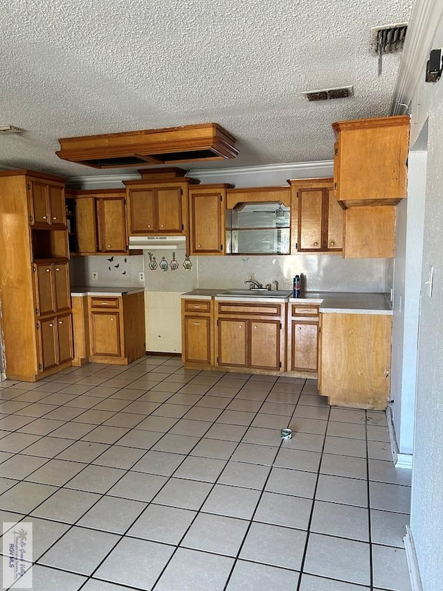 kitchen with a textured ceiling, decorative backsplash, light tile patterned floors, and sink