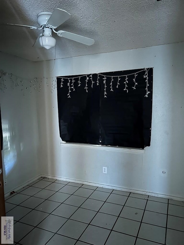 tiled spare room featuring a textured ceiling and ceiling fan