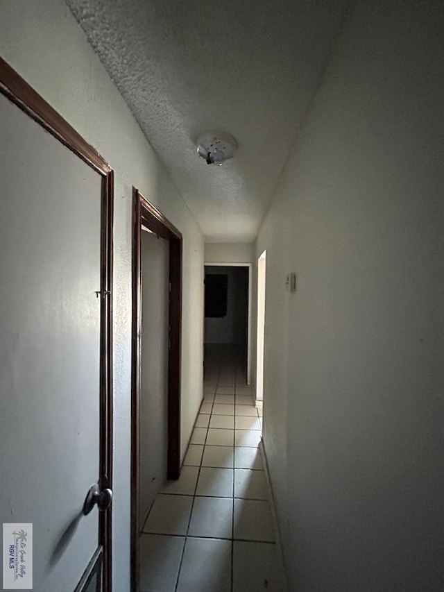 hall featuring a textured ceiling and light tile patterned flooring