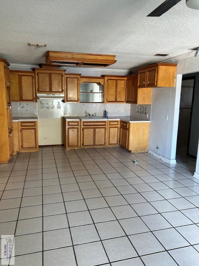 kitchen featuring ceiling fan, sink, tasteful backsplash, a textured ceiling, and light tile patterned floors