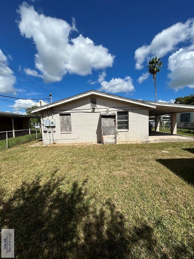 rear view of property featuring a carport and a yard