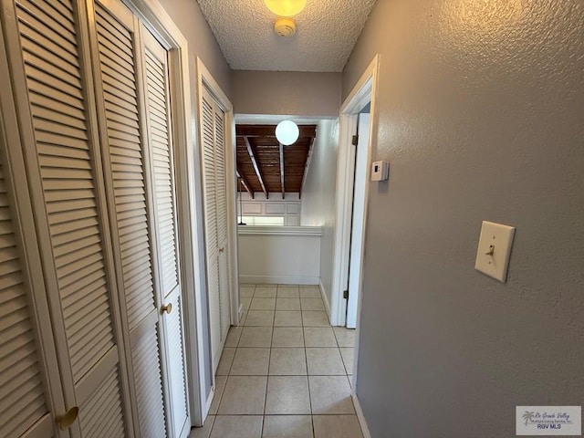 2100 W San Marcelo Blvd Unit 216, Brownsville, TX 78526 - hall featuring light tile patterned floors, a textured ceiling, baseboards, and a textured wall