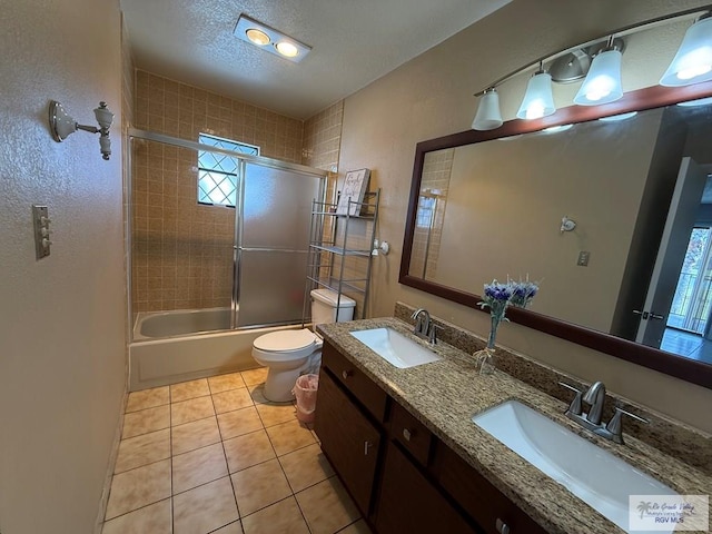 2100 W San Marcelo Blvd Unit 216, Brownsville, TX 78526 - bathroom featuring toilet, tile patterned flooring, a textured ceiling, double vanity, and bath / shower combo with glass door