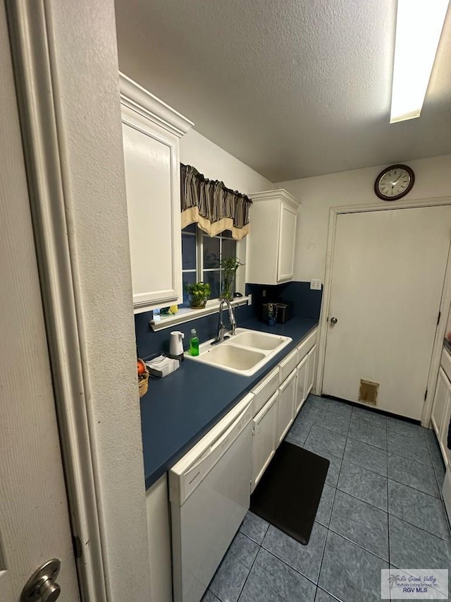 kitchen with sink, white dishwasher, white cabinetry, and tile patterned flooring