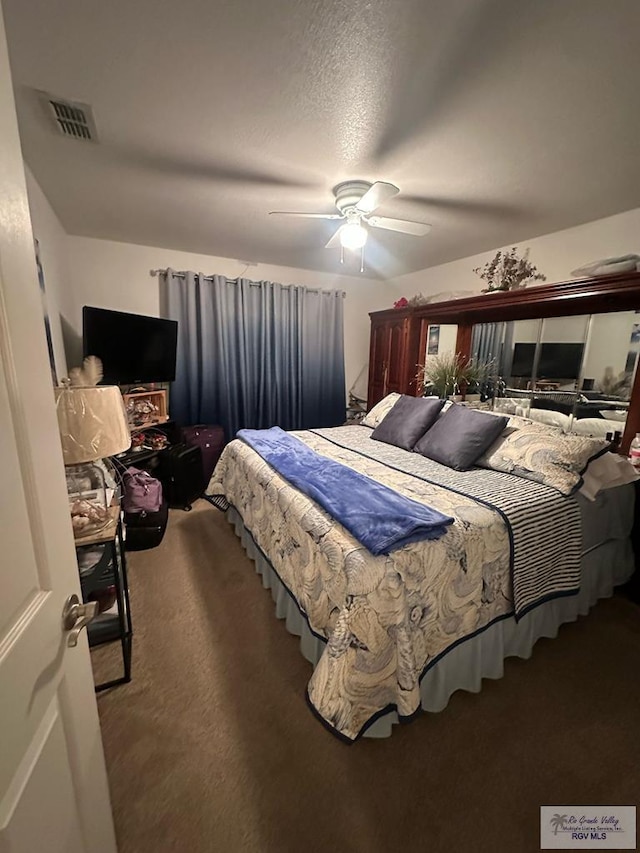 bedroom with ceiling fan, carpet flooring, and a textured ceiling