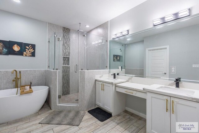 bathroom with vanity, separate shower and tub, and tile walls