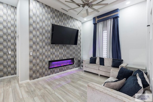 living room featuring ceiling fan, a large fireplace, and wood-type flooring