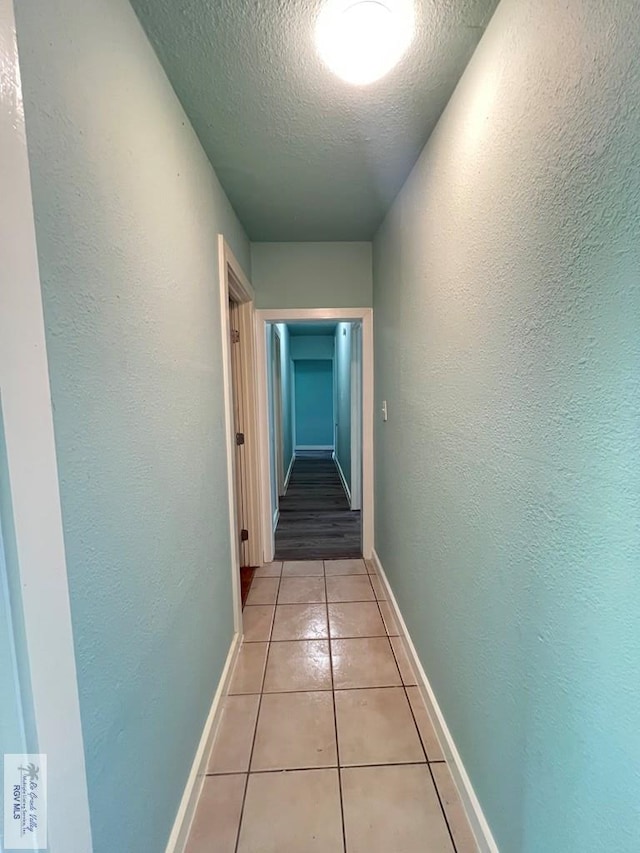 hall with light tile patterned floors and a textured ceiling