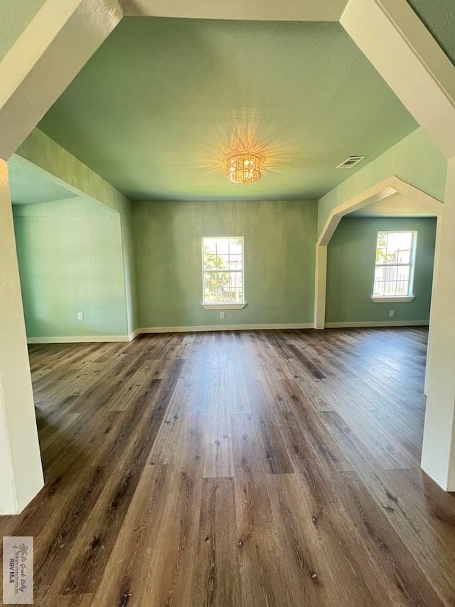 bonus room with hardwood / wood-style flooring and an inviting chandelier