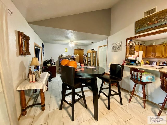 tiled dining area with ceiling fan and lofted ceiling