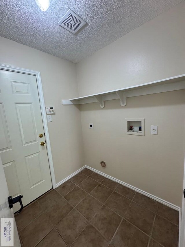 1072 Vamonos Dr, Brownsville, TX 78526 - clothes washing area with hookup for an electric dryer, hookup for a washing machine, a textured ceiling, dark tile patterned floors, and baseboards