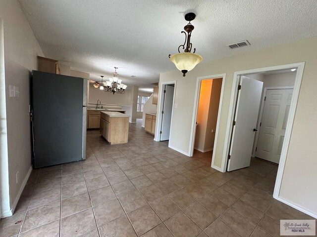1072 Vamonos Dr, Brownsville, TX 78526 - kitchen featuring freestanding refrigerator, light countertops, a chandelier, a textured ceiling, and a center island