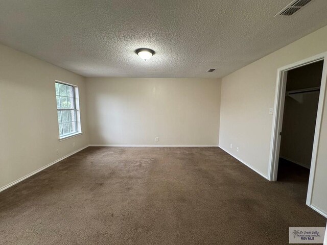 1072 Vamonos Dr, Brownsville, TX 78526 - spare room with dark carpet, baseboards, and a textured ceiling