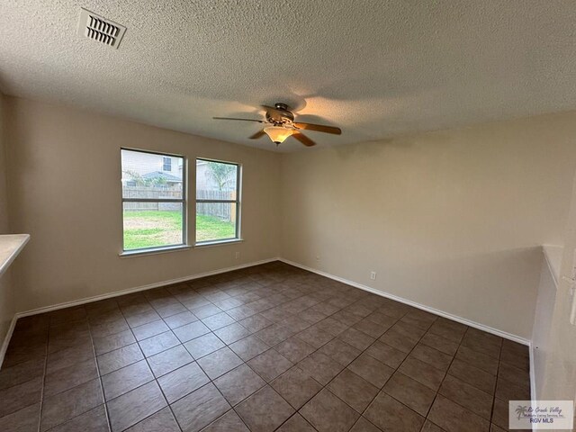 1072 Vamonos Dr, Brownsville, TX 78526 - unfurnished room featuring ceiling fan, dark tile patterned floors, a textured ceiling, and baseboards