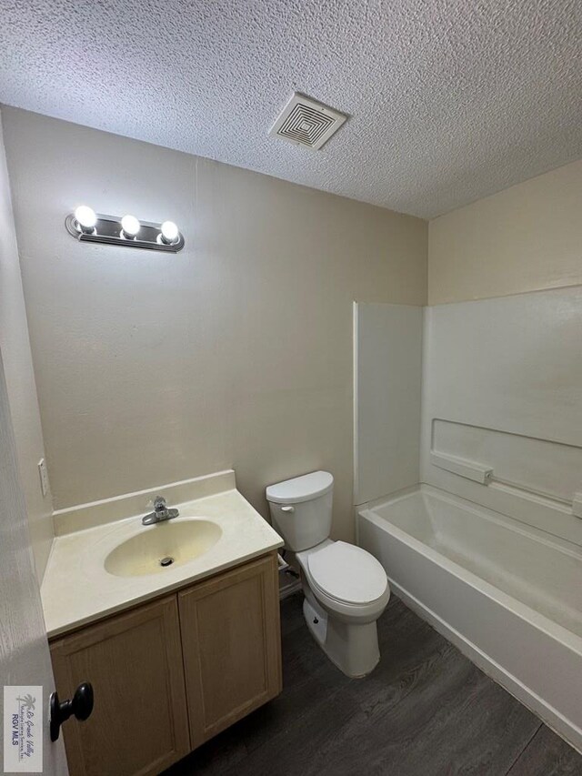 1072 Vamonos Dr, Brownsville, TX 78526 - bathroom featuring wood finished floors, toilet, vanity, a textured ceiling, and shower / bath combination