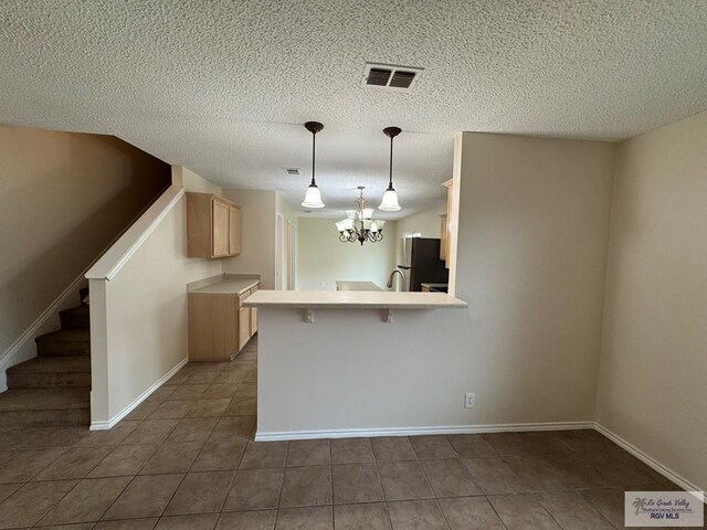 1072 Vamonos Dr, Brownsville, TX 78526 - kitchen featuring freestanding refrigerator, tile patterned floors, a kitchen breakfast bar, light countertops, and a chandelier
