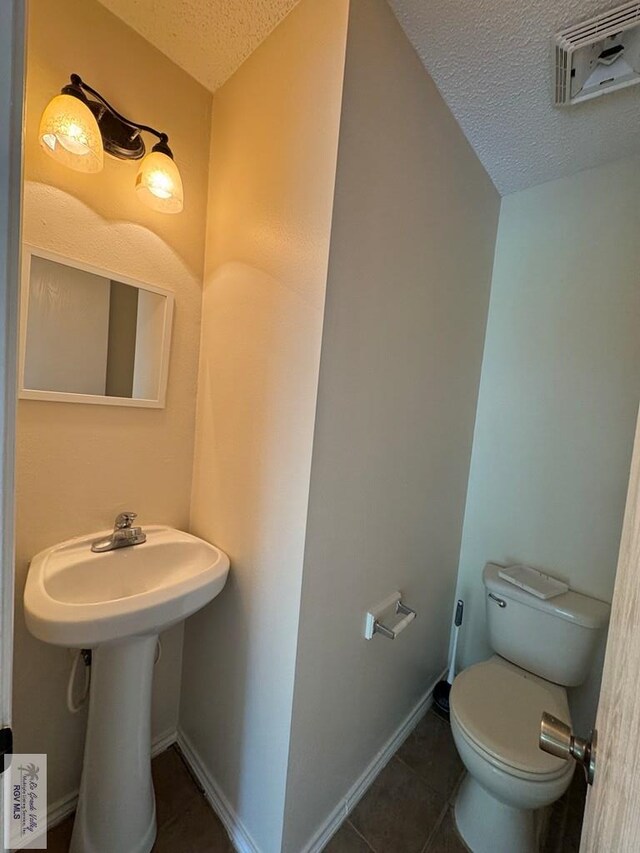 1072 Vamonos Dr, Brownsville, TX 78526 - bathroom with a textured ceiling, toilet, tile patterned floors, and baseboards