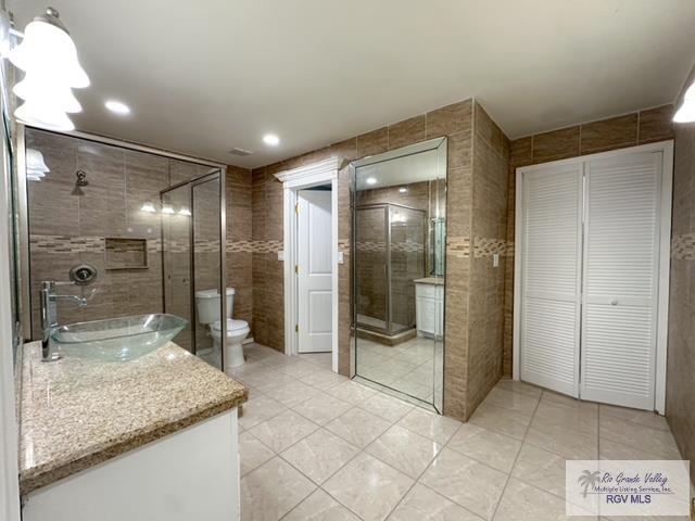 bathroom featuring tile patterned floors, vanity, toilet, and tile walls