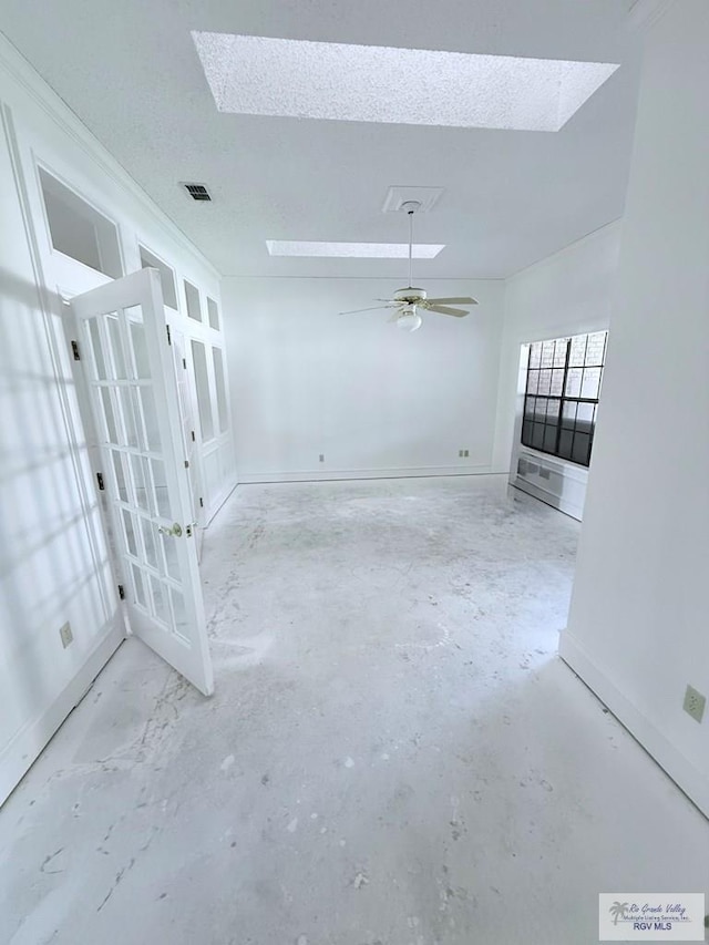 unfurnished room with ceiling fan, a textured ceiling, and a skylight