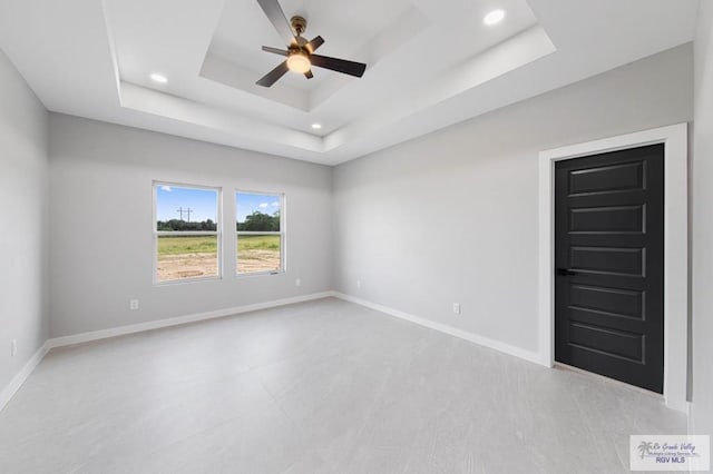 unfurnished room featuring a raised ceiling and ceiling fan