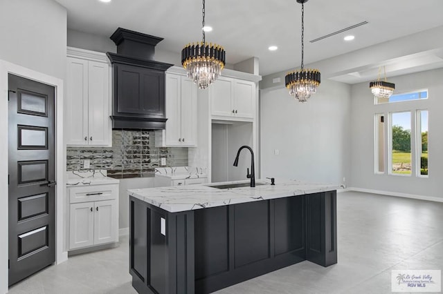 kitchen featuring pendant lighting, white cabinetry, and a kitchen island with sink