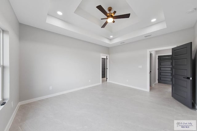 unfurnished bedroom with ceiling fan and a raised ceiling