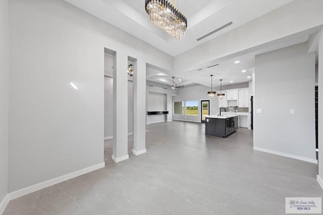 unfurnished living room with sink and ceiling fan with notable chandelier