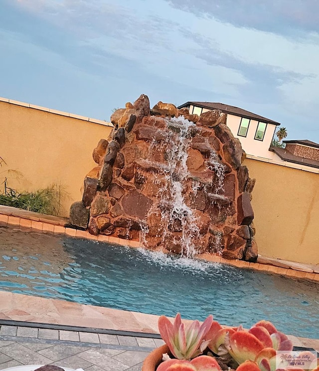 view of swimming pool with pool water feature