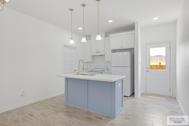 kitchen with light wood-type flooring, white appliances, sink, a center island with sink, and hanging light fixtures