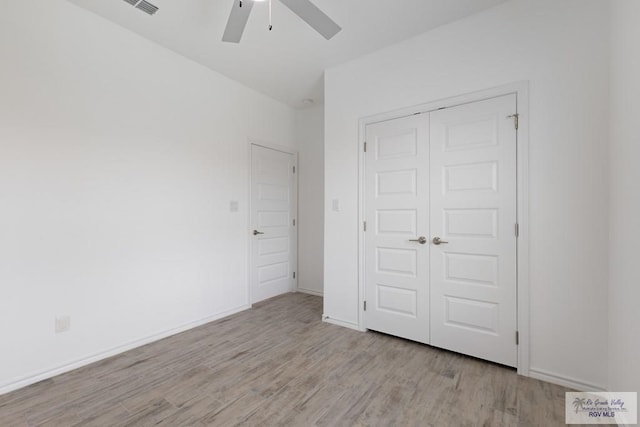 unfurnished bedroom with ceiling fan, light wood-type flooring, and a closet