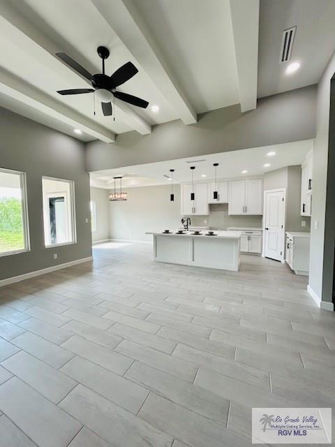 521 Valley Oak Cir, Los Fresnos, TX 78566 - unfurnished living room featuring baseboards, recessed lighting, beamed ceiling, ceiling fan, and a chandelier