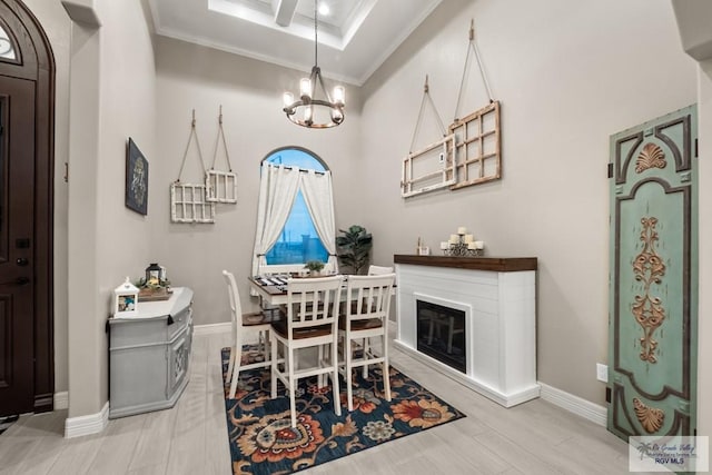 dining space featuring crown molding, a raised ceiling, an inviting chandelier, and light hardwood / wood-style flooring