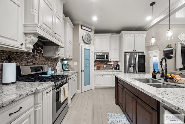 kitchen with sink, light stone counters, decorative light fixtures, appliances with stainless steel finishes, and white cabinets