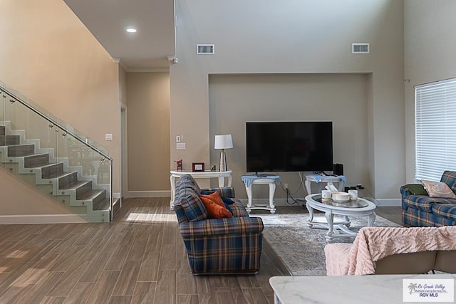 living room featuring hardwood / wood-style flooring and a towering ceiling