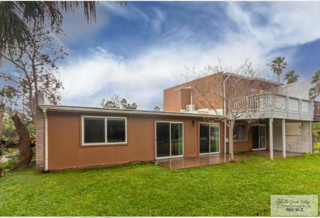 back of property featuring a lawn, a patio, and stucco siding