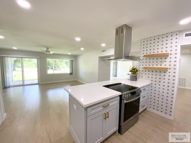 kitchen with visible vents, light wood-style floors, baseboards, island range hood, and stainless steel electric stove