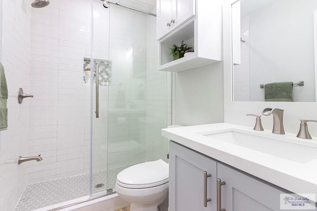 bathroom featuring toilet, a shower stall, and vanity