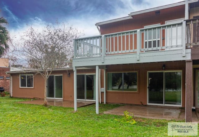 rear view of property with a lawn, a wooden deck, and a patio area