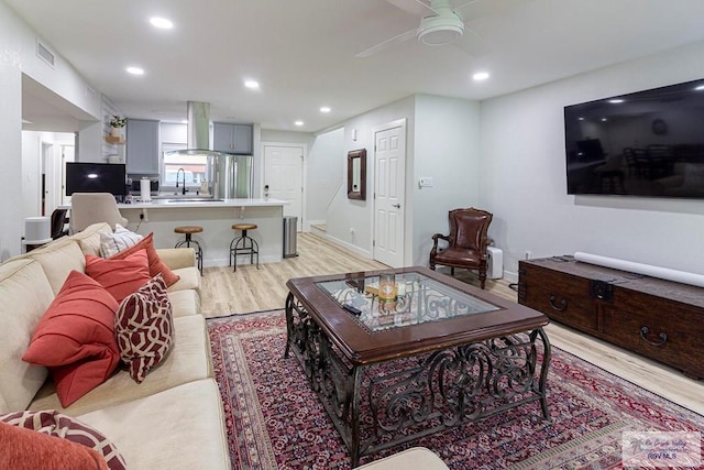 living room with light hardwood / wood-style floors, ceiling fan, and sink