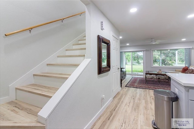 staircase featuring ceiling fan and wood-type flooring